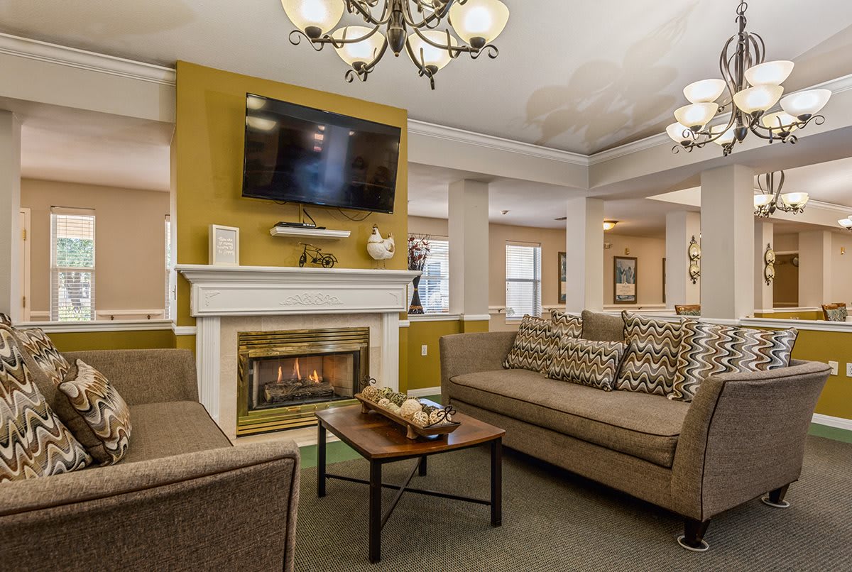 A cozy living room with a fireplace, comfortable sofas, and a mounted television.