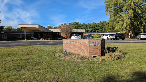 A brick sign in front of a building with a clear blue sky above.