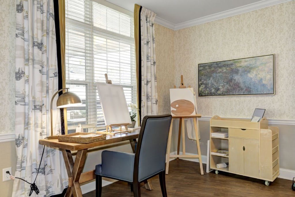 A well-lit art studio with easels and a desk by the window.