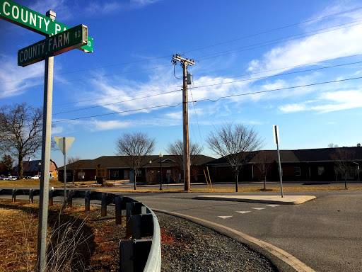 A quiet intersection with a clear blue sky and nearby buildings.