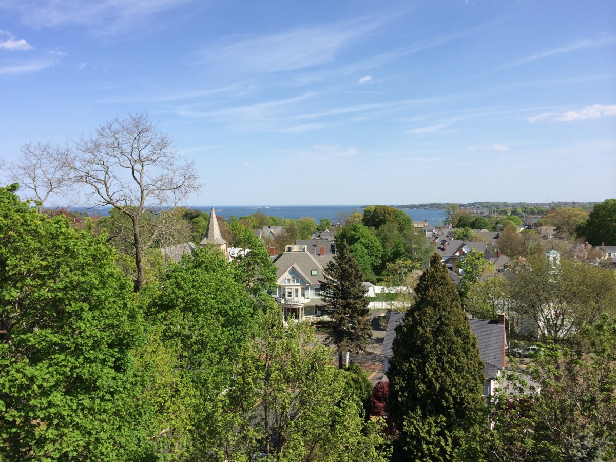 A scenic view of a village with a church steeple, surrounded by lush greenery and set against a clear blue sky.