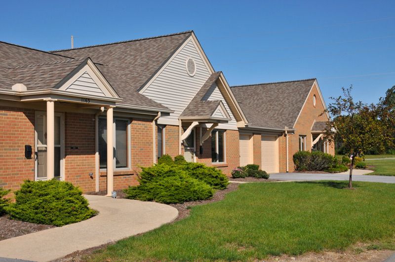 A row of suburban houses with well-maintained lawns and driveways.