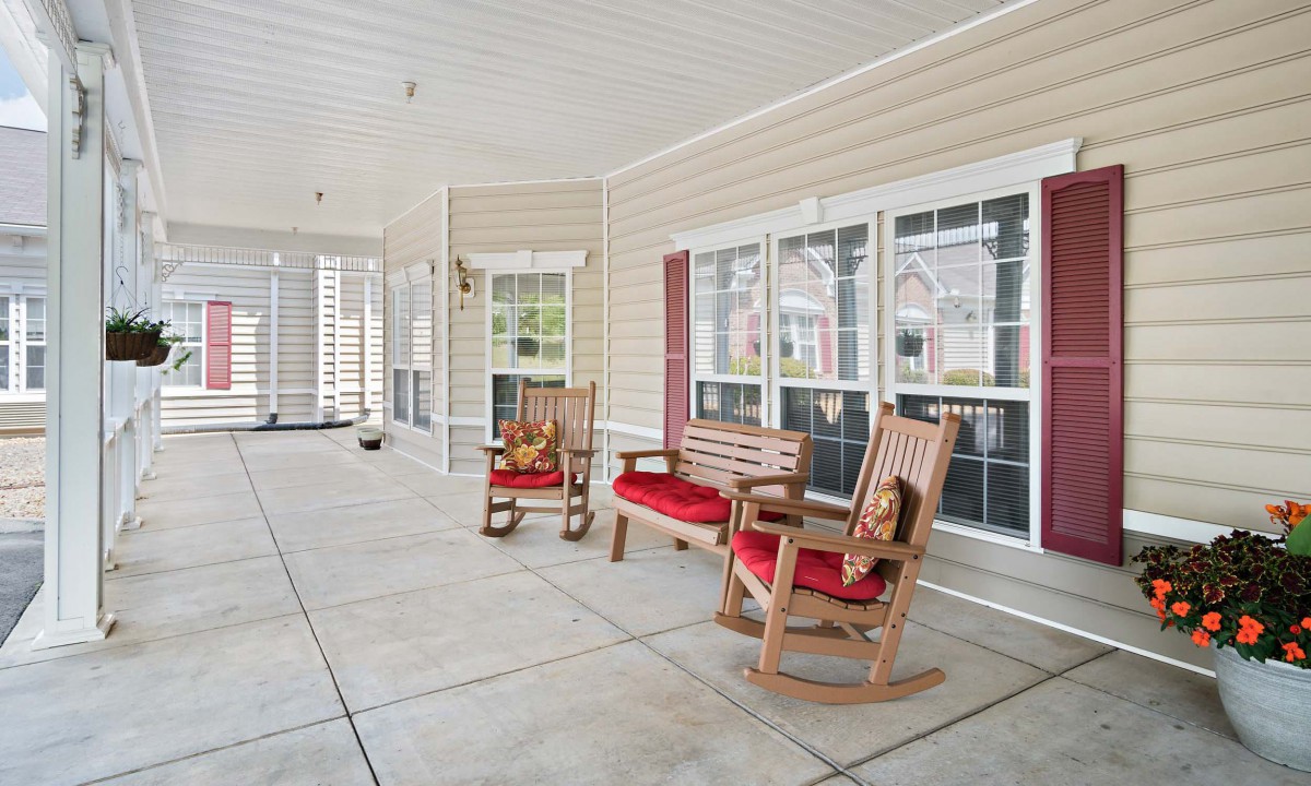 A cozy porch with rocking chairs and a bench, perfect for relaxing outdoors.
