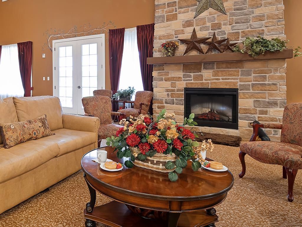 A cozy living room featuring a stone fireplace, comfortable seating, and a well-decorated coffee table.