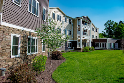 A beautifully landscaped apartment building with a well-maintained lawn under a clear blue sky.