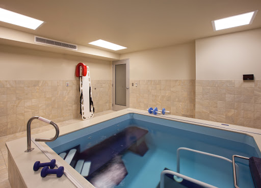 A serene indoor spa pool area featuring exercise equipment and a relaxing environment.