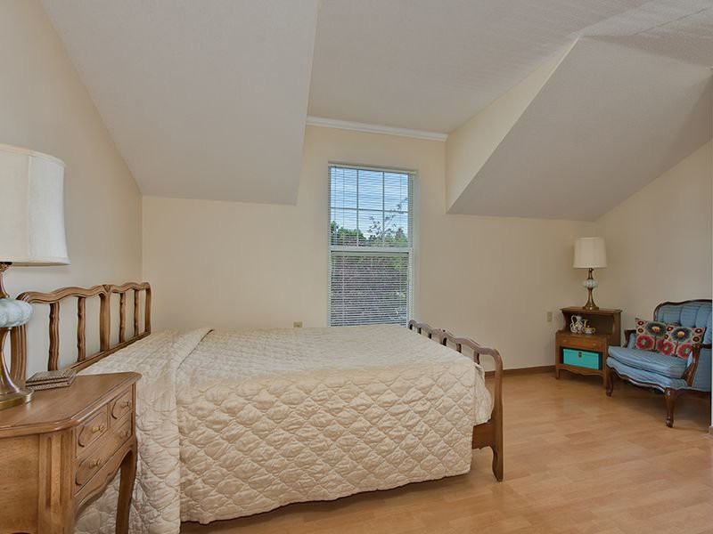 A cozy bedroom with a wooden bed, nightstand, and a large window.