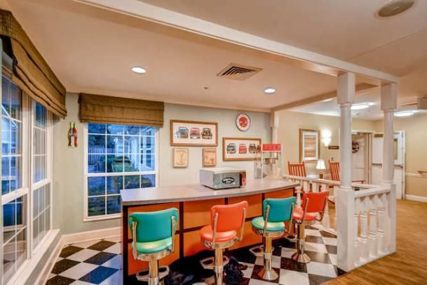 A retro diner interior with colorful bar stools and a classic checkerboard floor.