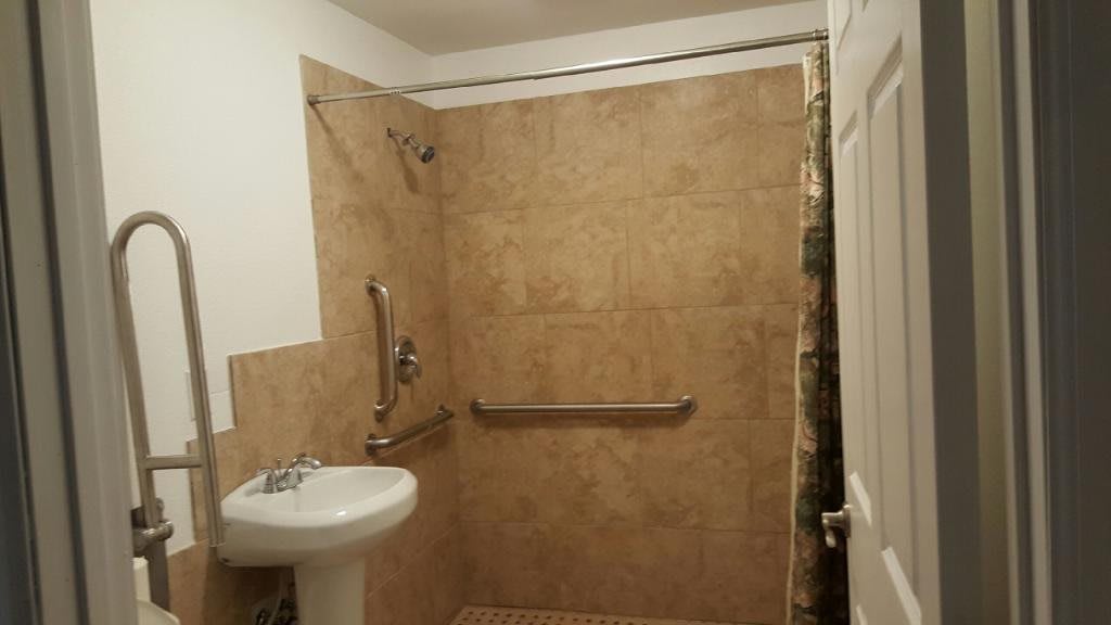 A modern bathroom with a tiled shower area and safety grab bars.
