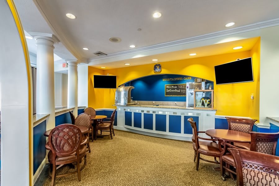 A cozy dining area with tables and a coffee station, featuring a bright blue and yellow color scheme.