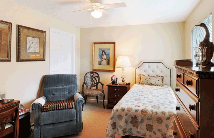 A cozy bedroom with a single bed, chair, and decorative artwork.