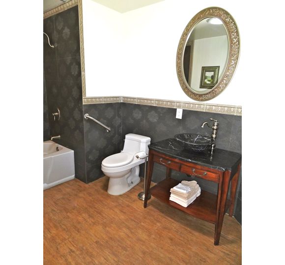 A modern bathroom featuring a toilet, stylish sink with a wooden vanity, and a large oval mirror.