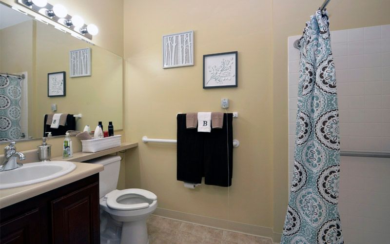 A neatly organized bathroom with a toilet, towels, and a patterned shower curtain.