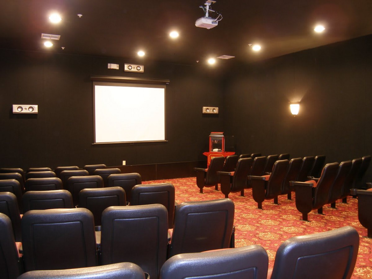 An empty theater room with a projection screen and rows of seating.