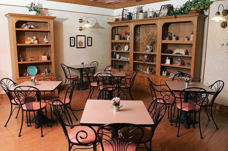 A cozy cafe interior with tables and chairs surrounded by decorative shelves.