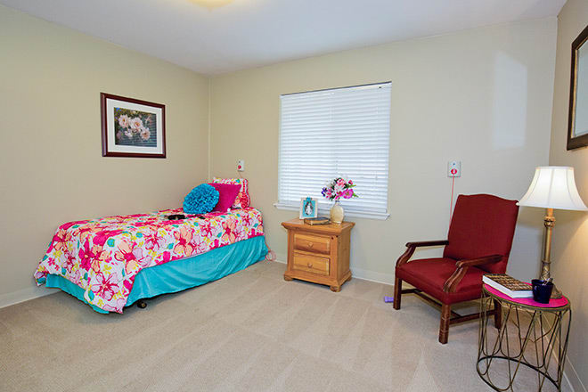 A cozy bedroom with a single bed, nightstand, and chair.