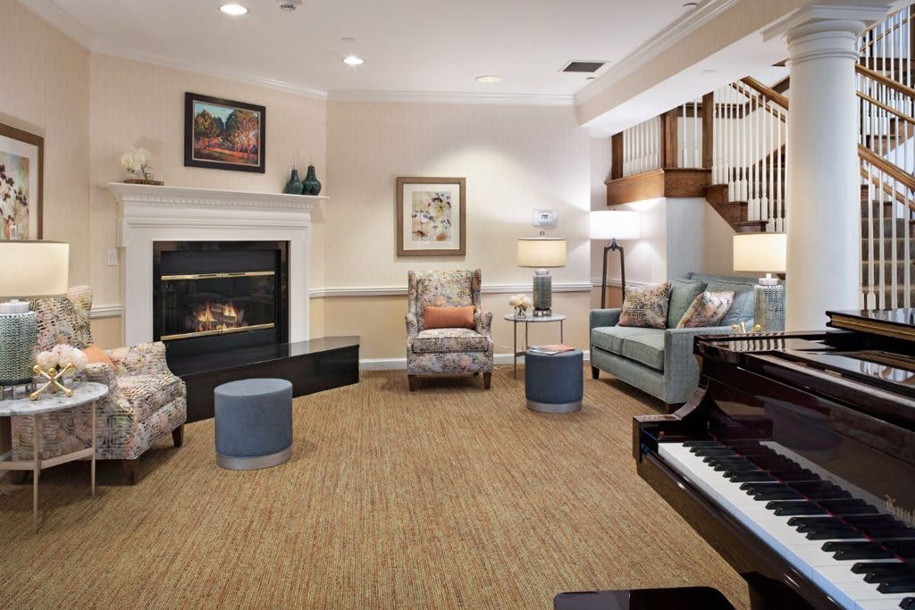 A cozy and elegant living room with a fireplace, piano, and comfortable seating.
