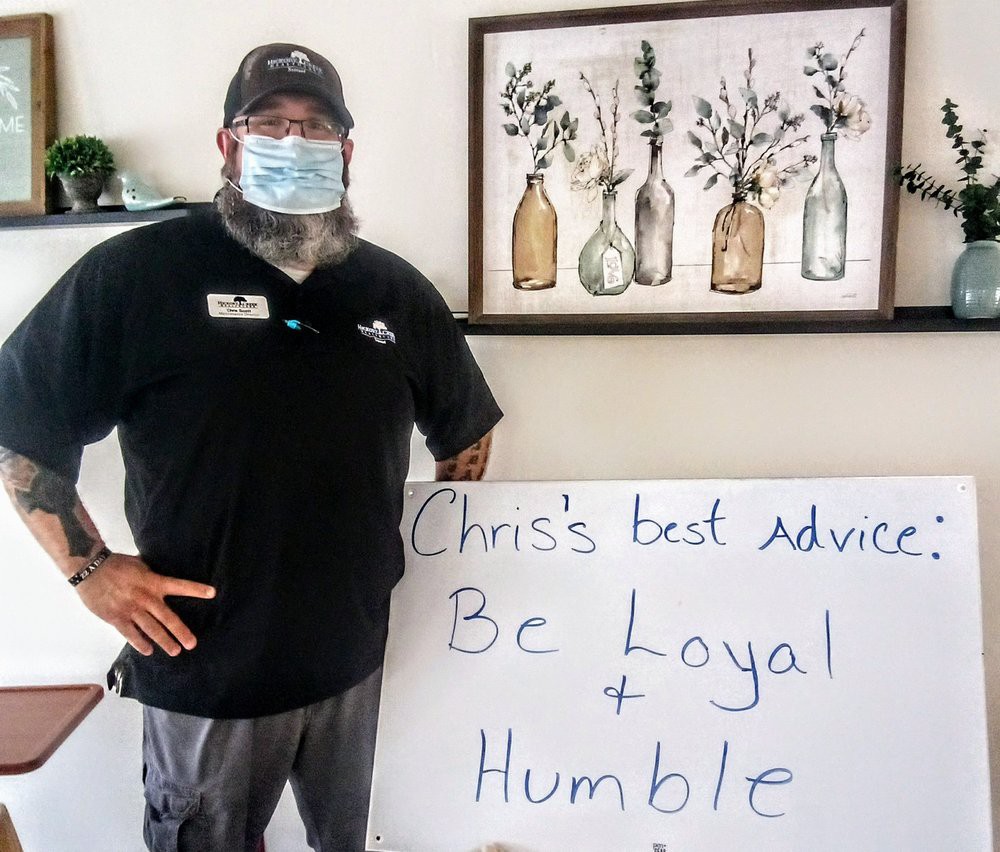Person sharing advice on a sign: 'Be Loyal + Humble'