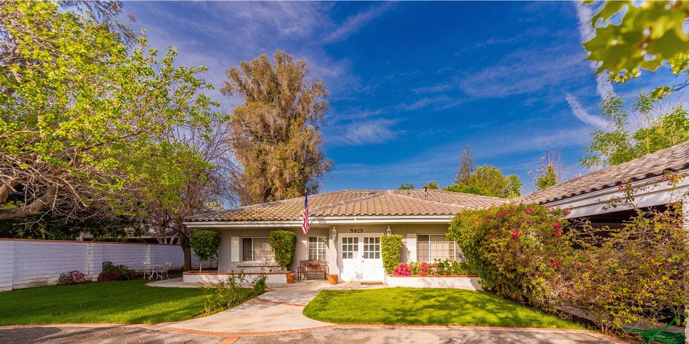 A charming suburban home with a well-maintained yard and clear blue sky.