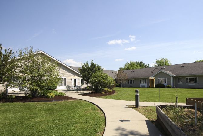 A peaceful residential building with a well-maintained lawn and pathway under a clear blue sky.
