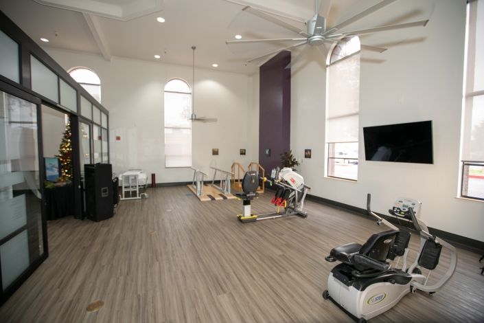 A modern gym with various exercise equipment in a spacious interior.