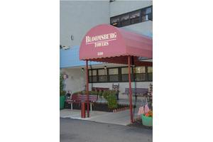 The entrance of a restaurant with a red awning and outdoor seating.