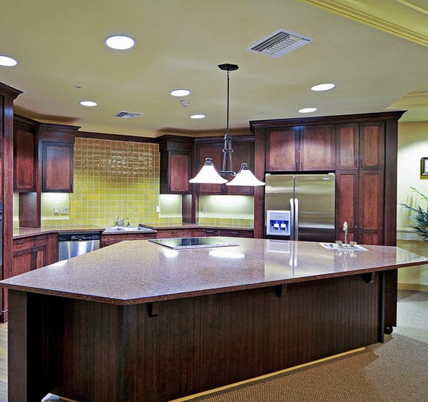 A modern kitchen featuring dark wood cabinets and an island counter with pendant lighting.