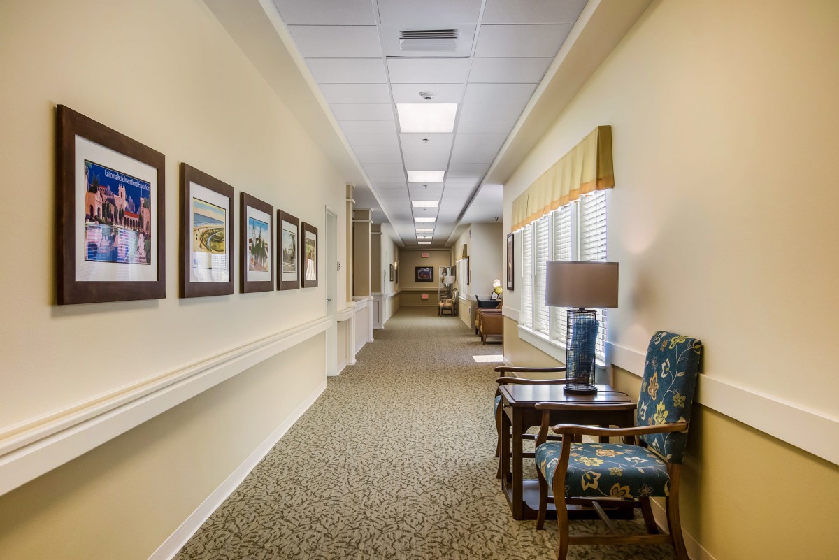A well-lit hallway with decorative pictures lining the walls and comfortable seating areas.