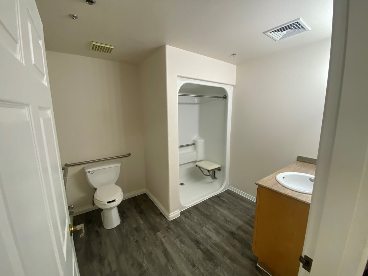 A modern bathroom with accessibility features including a shower seat and handrails.