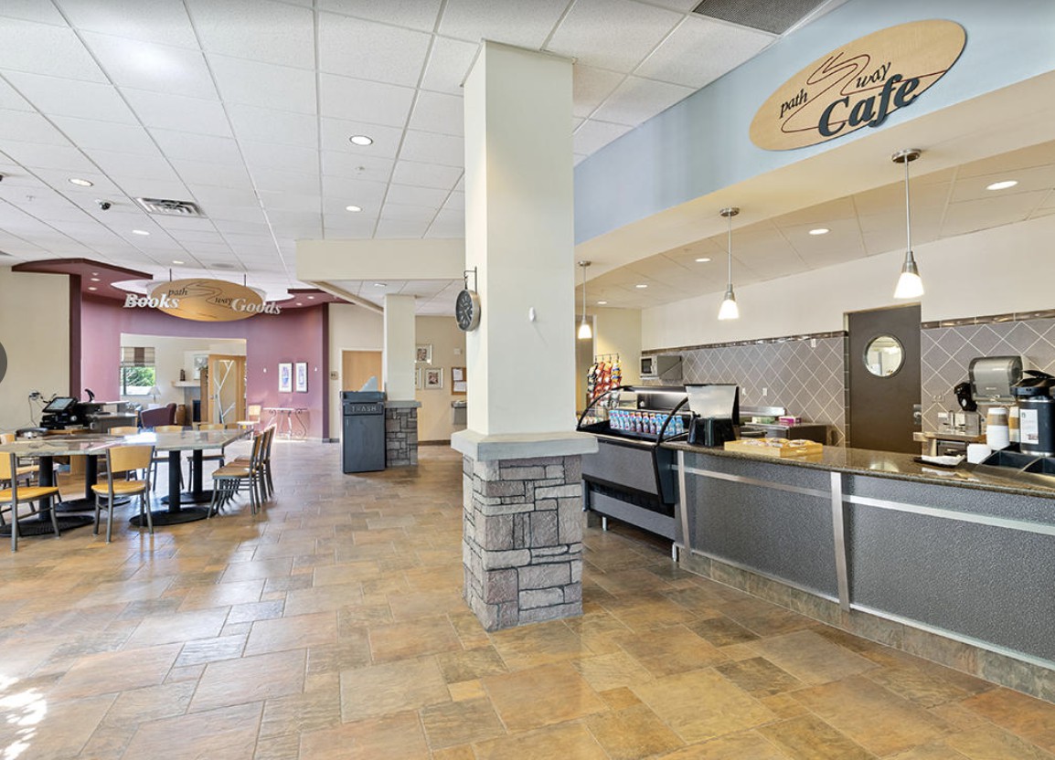 An empty cafe interior with a food service counter and seating area.