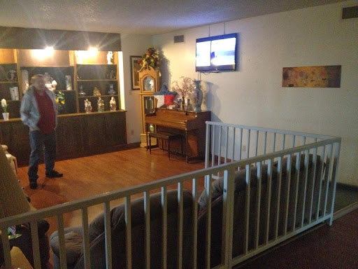 A cozy living room featuring a piano, trophies on display, and a TV.