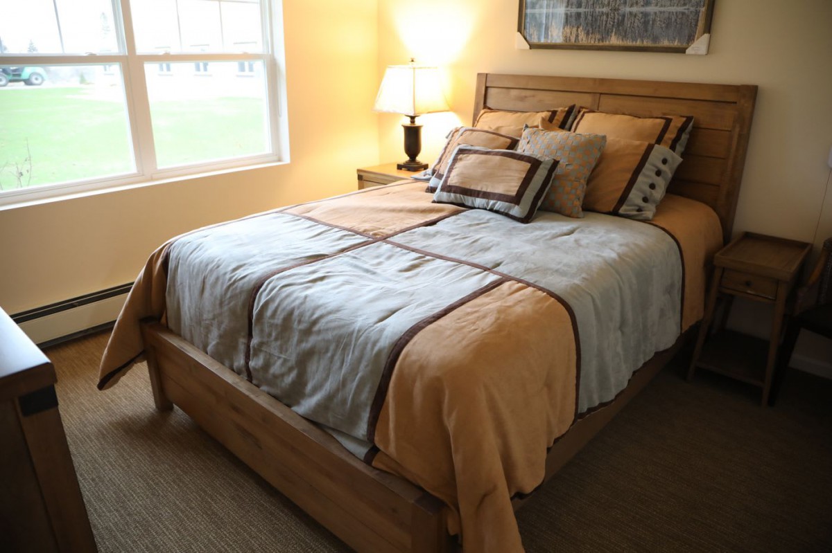 A cozy bedroom with a neatly made bed and warm lighting.