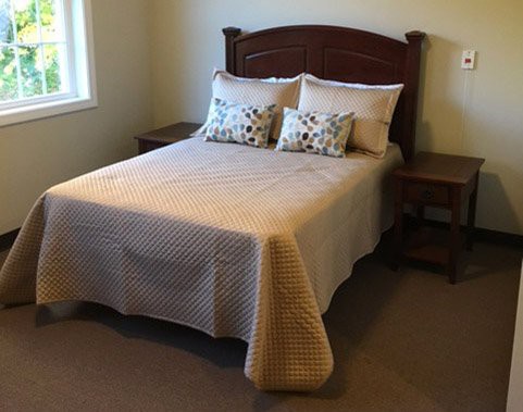A neatly made bed with decorative pillows and wooden side tables in a cozy bedroom.