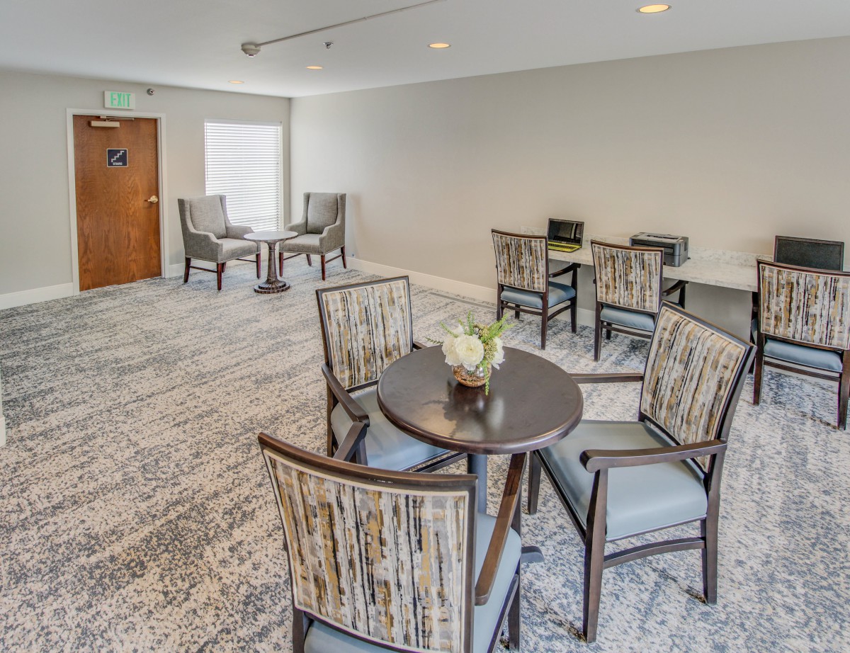 A cozy seating area with several tables and chairs arranged on a carpeted floor.