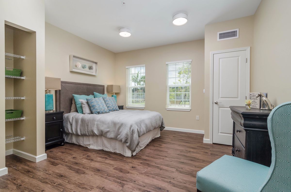A modern, minimalist bedroom featuring wood flooring and ample natural light.