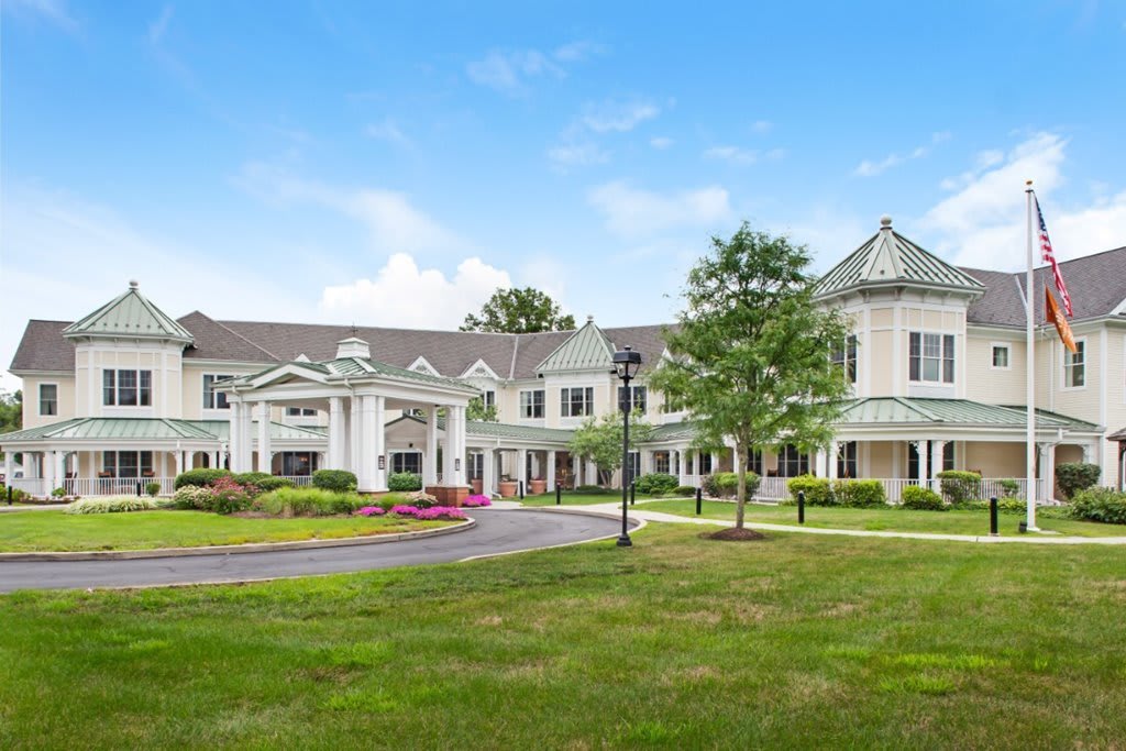 A large, elegant residential building with classic architecture and surrounding greenery under a clear blue sky.