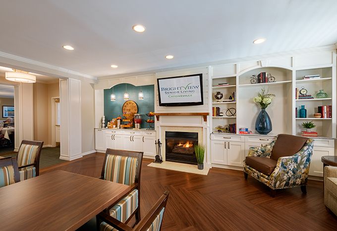 A cozy living room featuring a fireplace, built-in shelves, and a dining area with wood flooring.