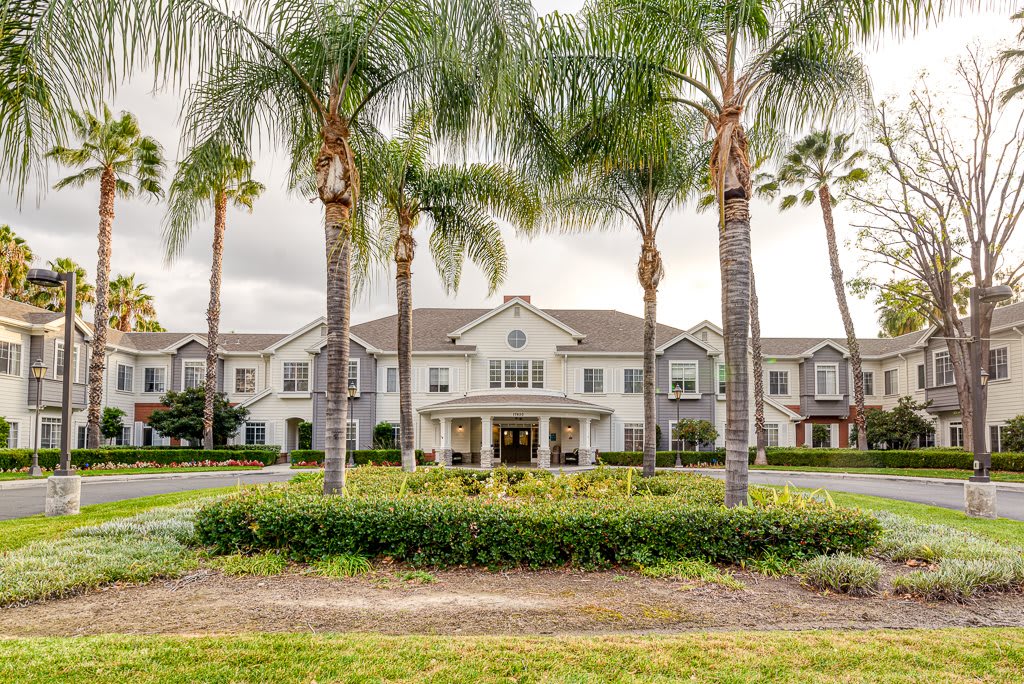 A grand residential building surrounded by palm trees and manicured landscaping.