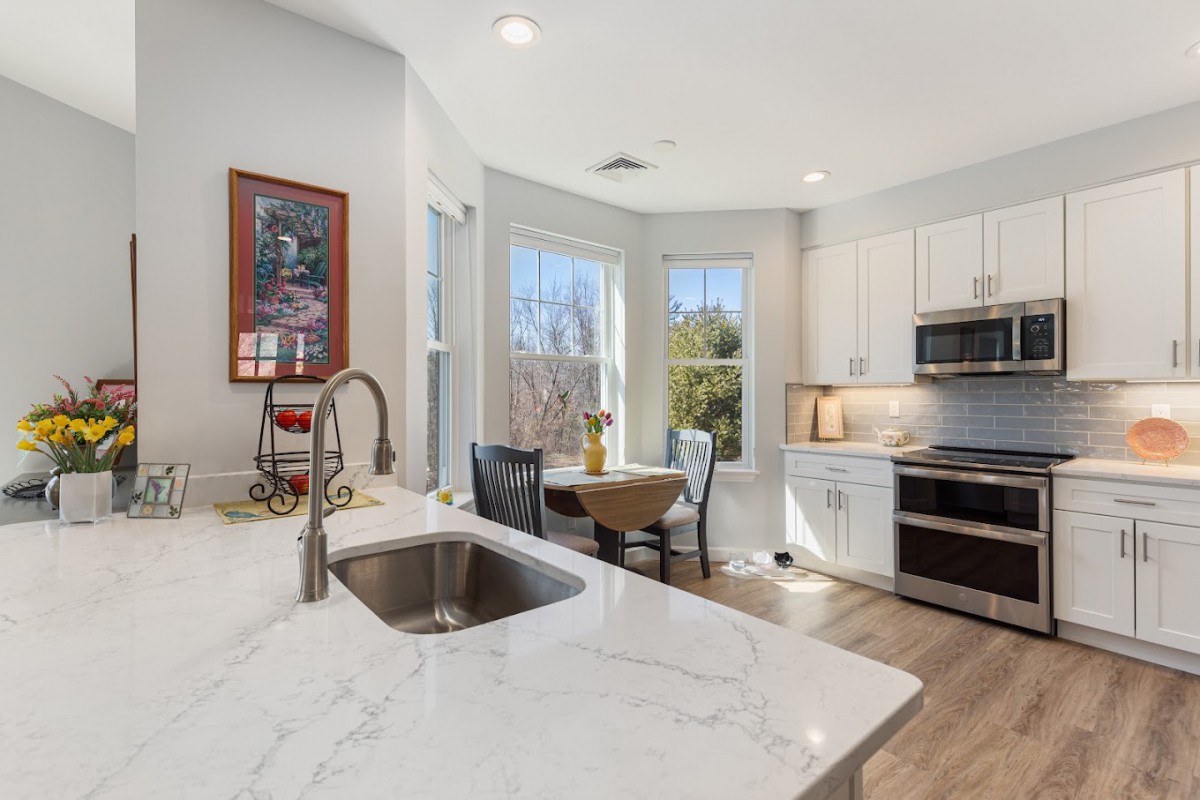 A modern kitchen with a marble countertop, stainless steel appliances, and a cozy dining area by the window.