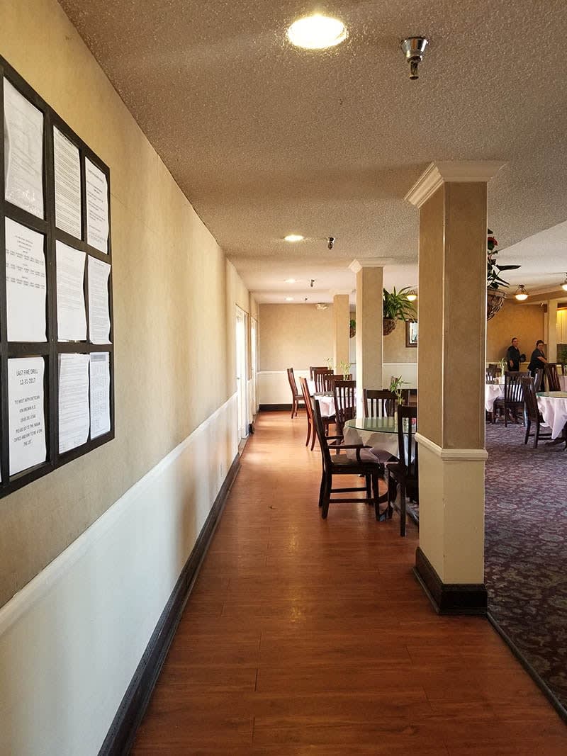 A corridor in a restaurant with tables and chairs lined along one side.