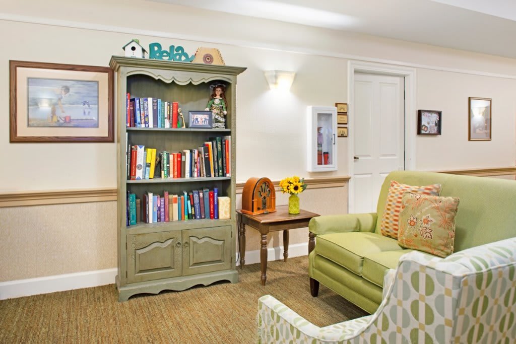 Cozy living room with a green sofa, colorful bookshelf, and homey decorations.