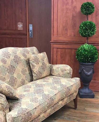 A cozy vintage-style sofa paired with decorative topiary in a warm wooden interior.