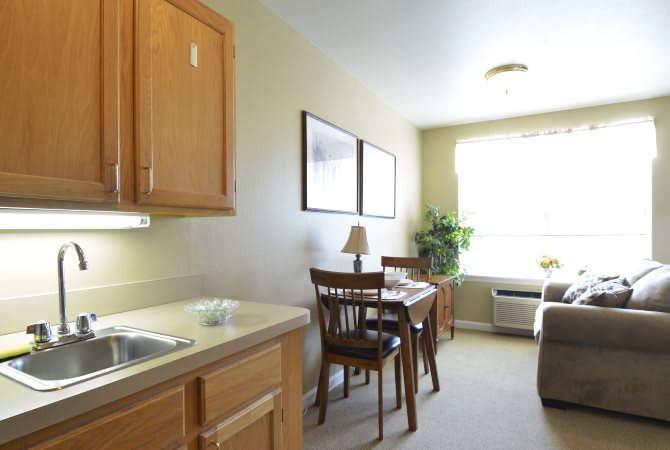 A small apartment kitchen and dining area with a table, chairs, and a window letting in natural light.