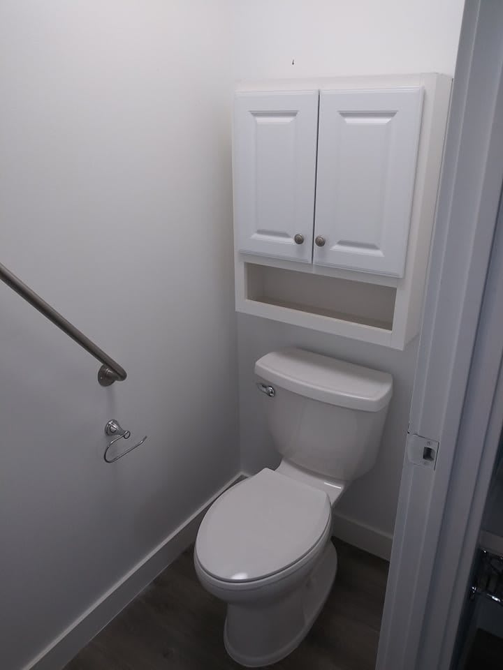 A minimalist bathroom with a toilet and wall-mounted cabinet.