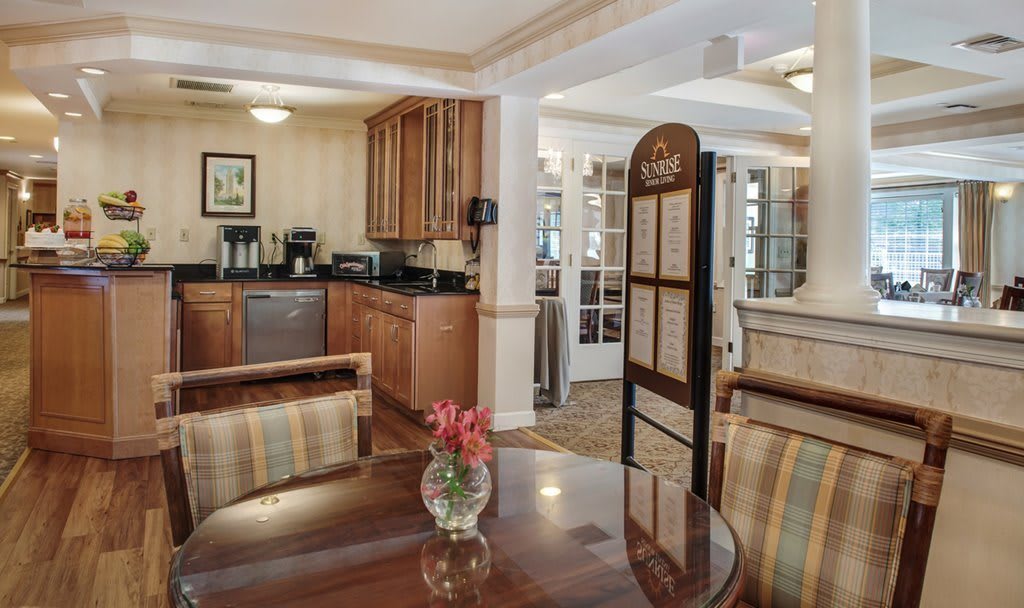 A cozy kitchen and dining area with wooden cabinets and a table decorated with flowers.