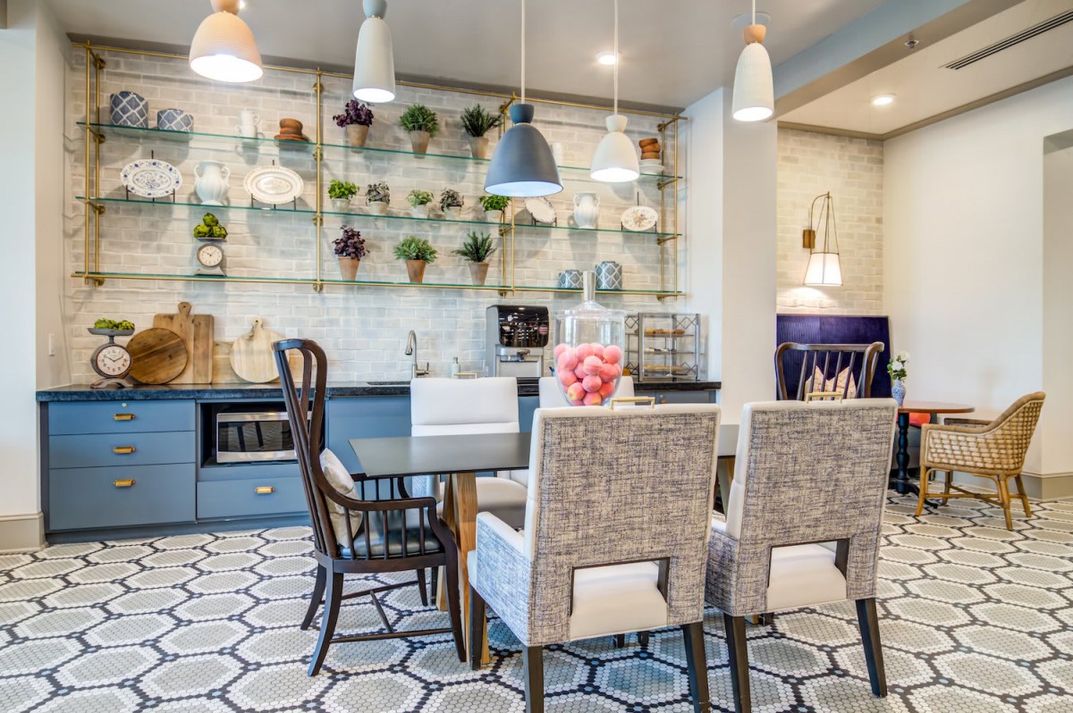 A stylish modern dining room featuring pendant lights, a mix of chairs around a table, and decorative shelving with plants.