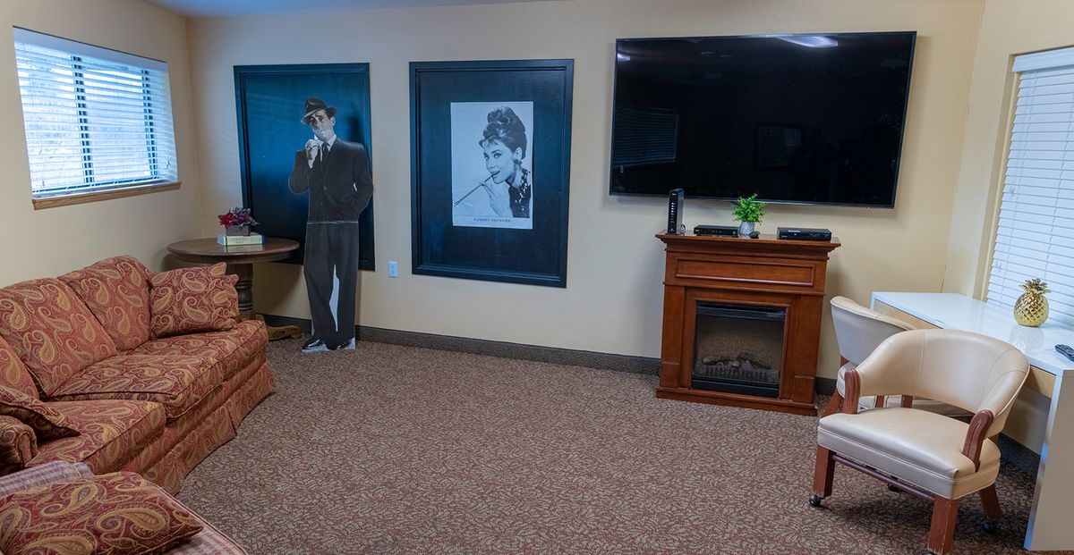A living room featuring a cardboard cutout, framed photo, television, and fireplace.