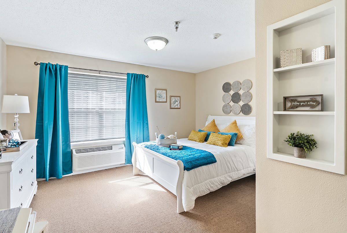 A cozy bedroom with a neatly made bed, accented by blue curtains and decorative pillows.
