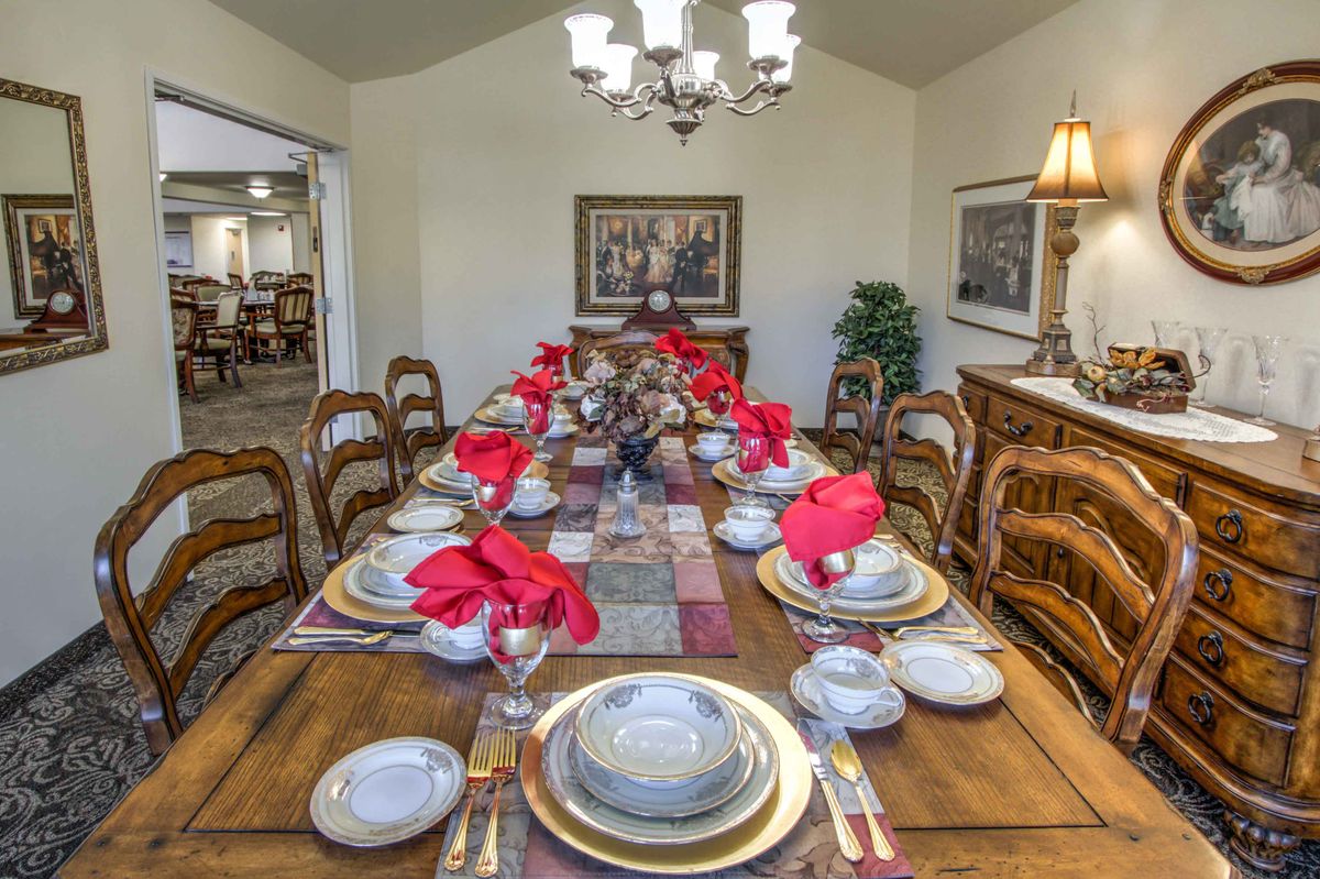 A formal dining room with an elegantly set table adorned with red napkins and stylish dinnerware.