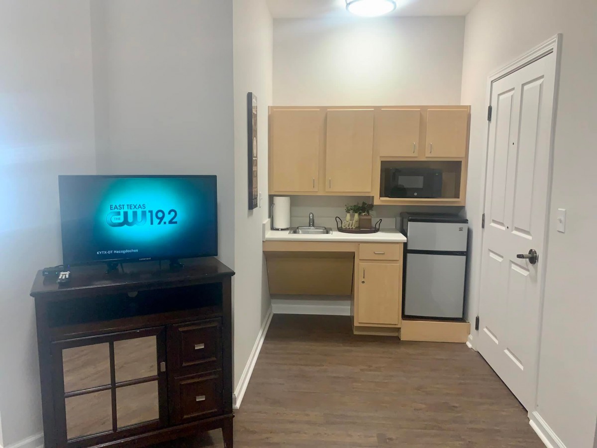 Compact apartment kitchen with a TV and basic appliances.